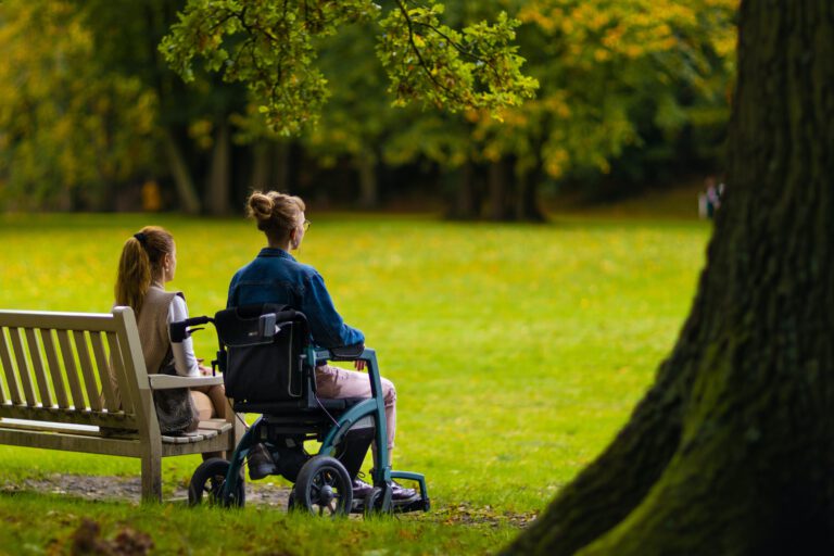 Frau im Rollstuhl mit Begleiterin im Park